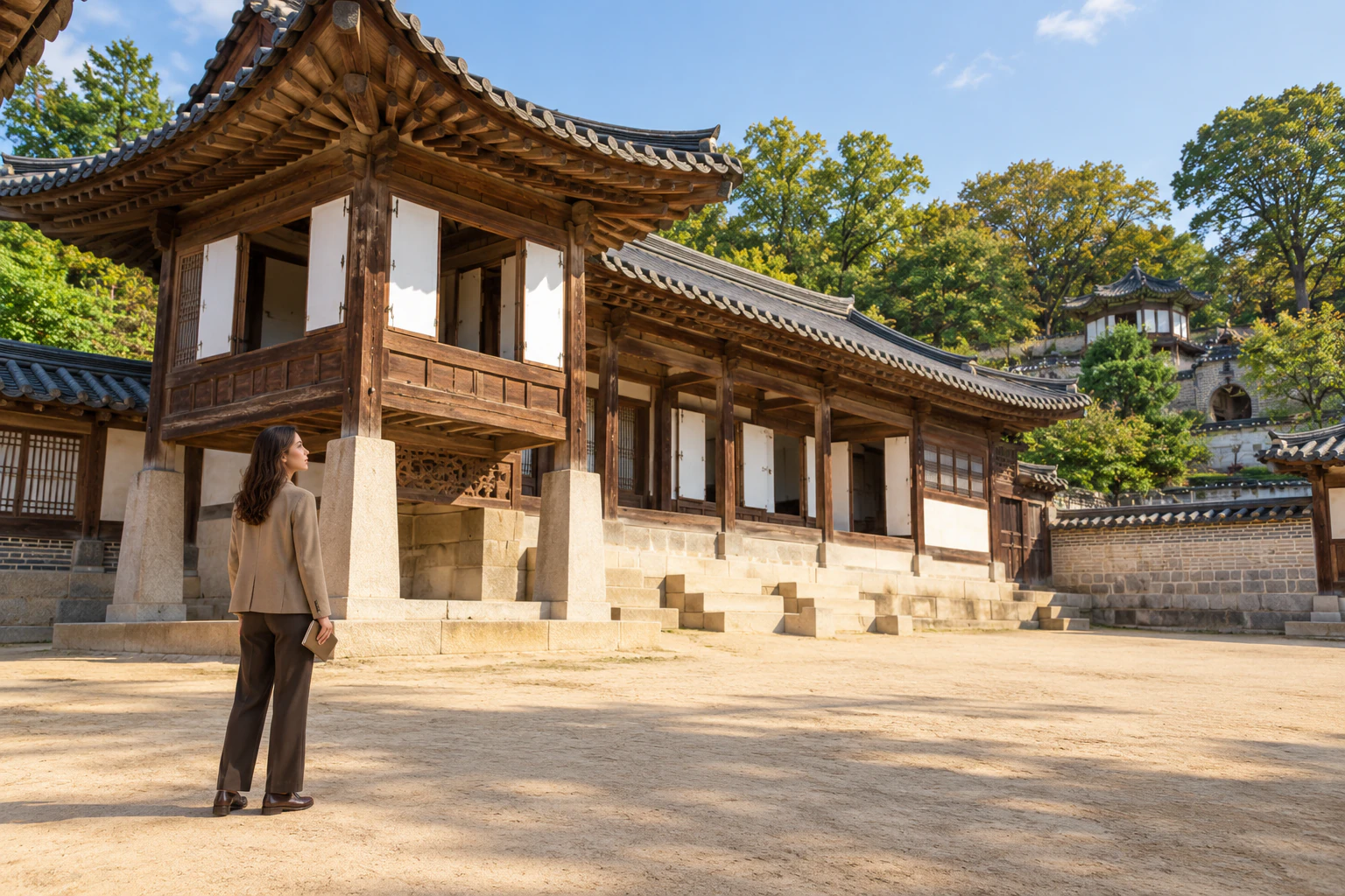站在泥土院子裡、抬頭看韓屋高樓廳的駝色外套年輕女性。編輯圖片。