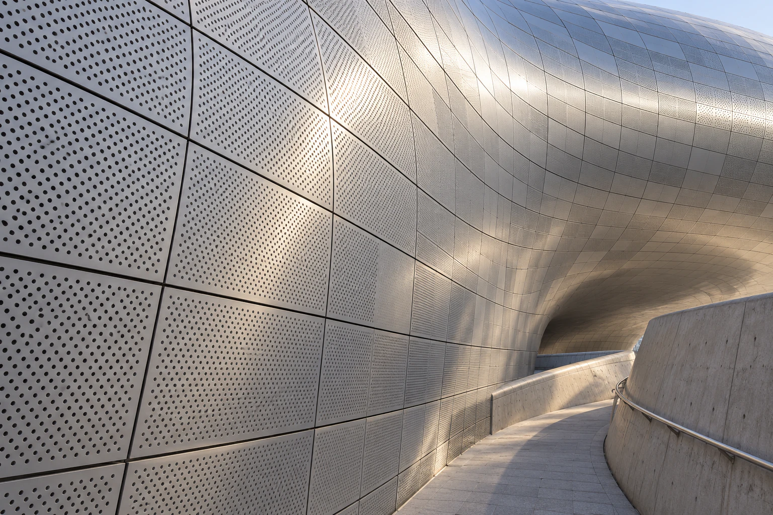 Close view of a curved facade of silver metal panels, each slightly different in size and curve. No people. Editorial image.