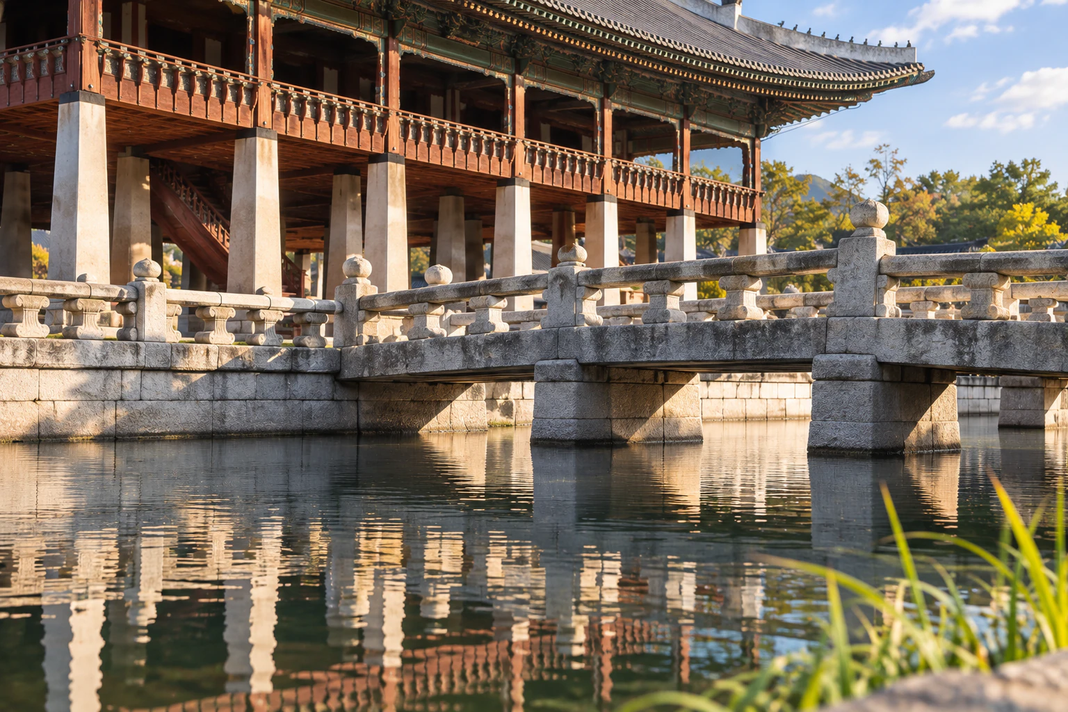 A low stone bridge with railings over a pond, no people. Editorial image.