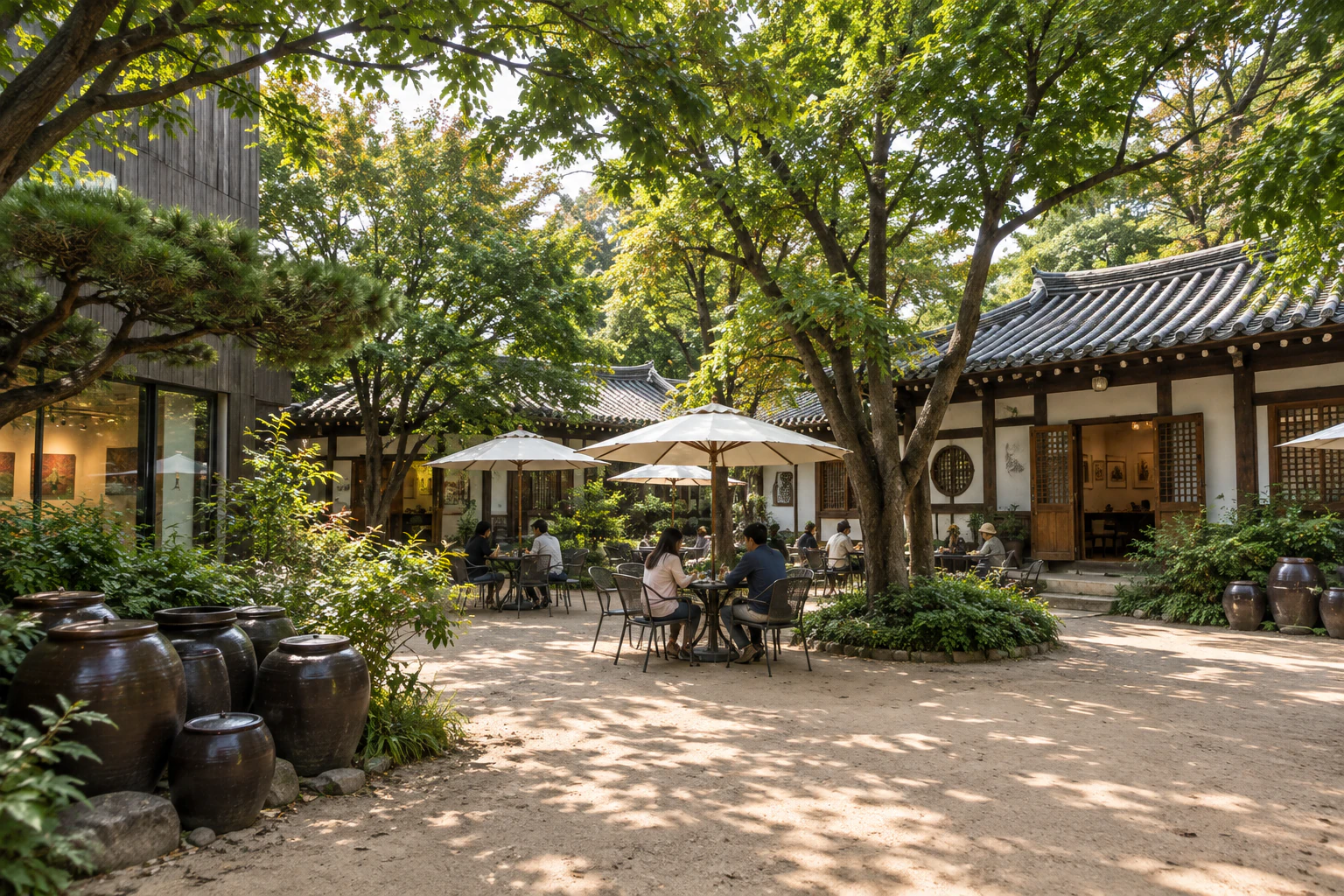 A sandy courtyard under big trees, tiled-roof hanok all around, iron tables under white parasols, onggi jars, and an exhibition hall with a dark timber facade to one side. Editorial image.