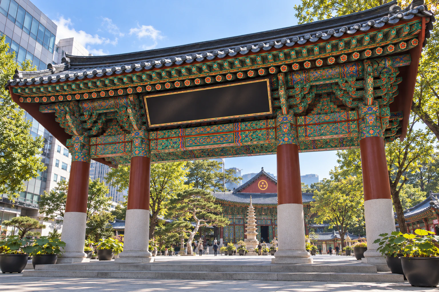 A wide temple gate with four red columns in a single row and vividly painted brackets under a tiled roof, seen from below, name board blank. Editorial image.