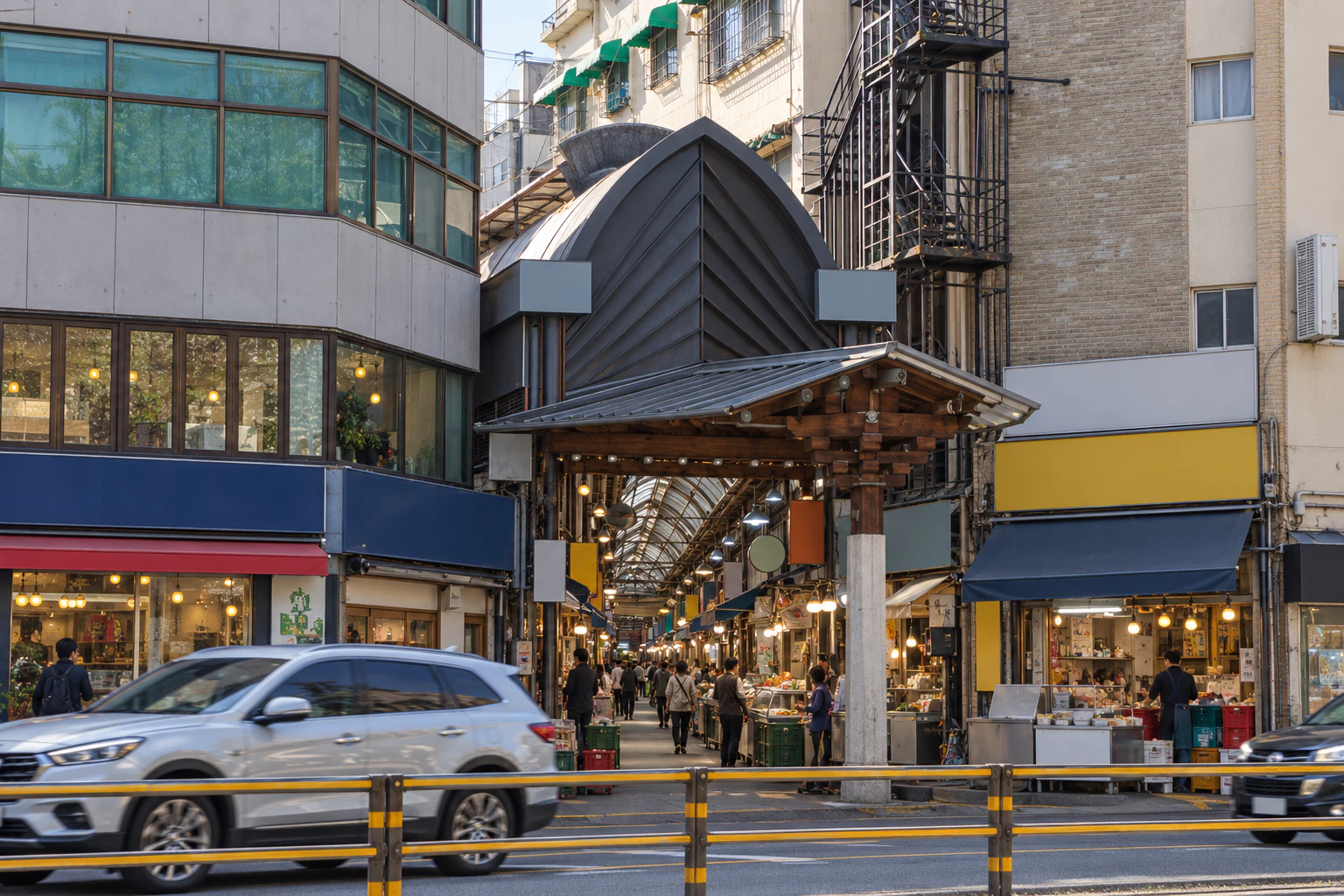 A market entrance seen from across the road: an arched-roof gateway with a smaller wooden-eaved gate beneath it, low buildings on either side. No lettering. Editorial image.