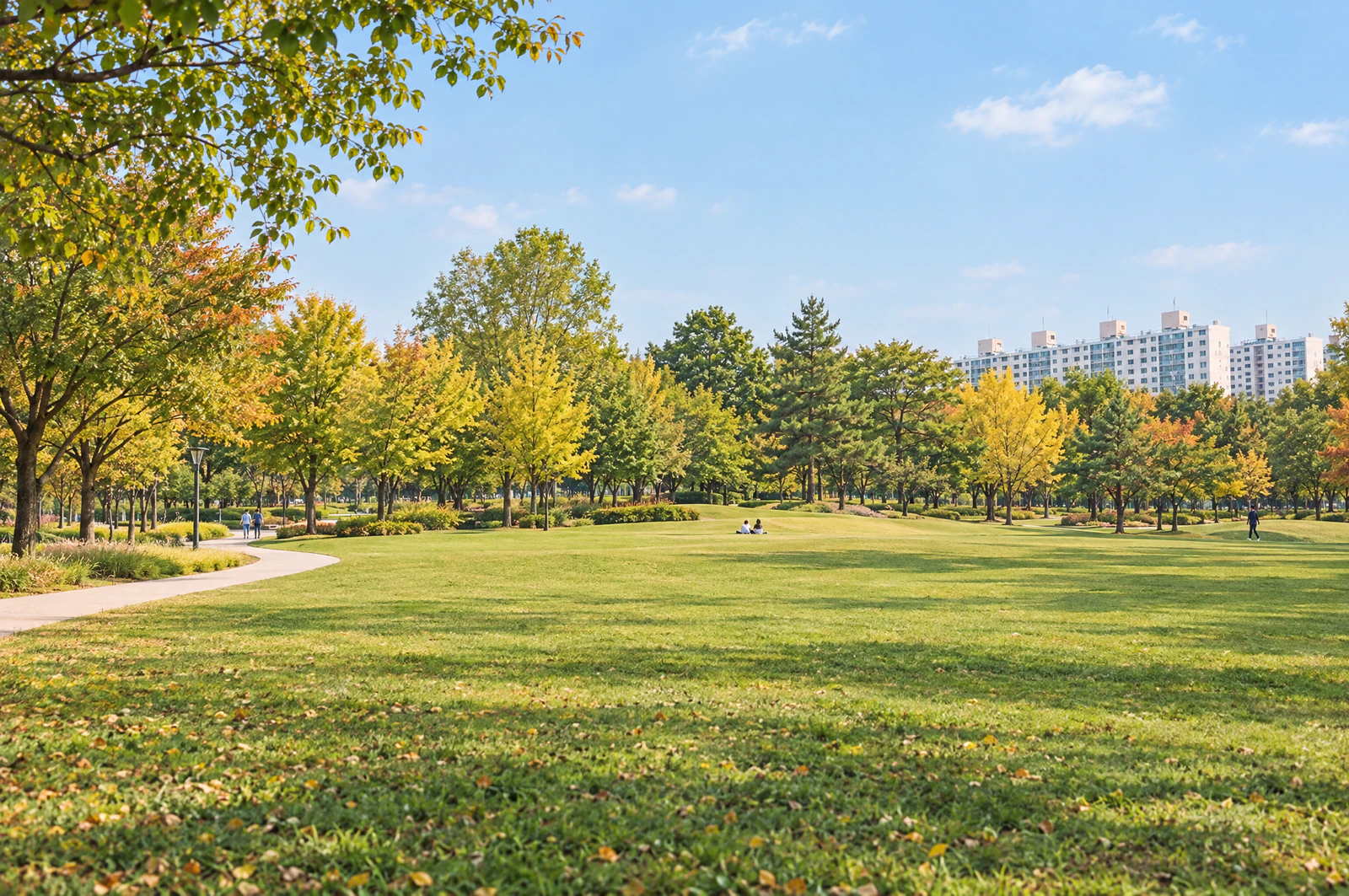 A wide lawn spreading along a gentle rise, ringed by trees, with apartment buildings in the distance. People small and distant. No lettering. Editorial image.