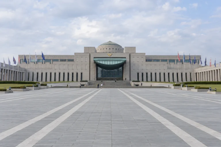 The War Memorial of Korea: One Straight Line from the Plaza to the Door — Noah Walks Up from Exit 12 of Samgakji Station, Follows the Centre Line of a Wide Plaza past the Colonnades on Either Side, and Slows Down All the Way to the Entrance of the Memorial Hall, Closed for Works