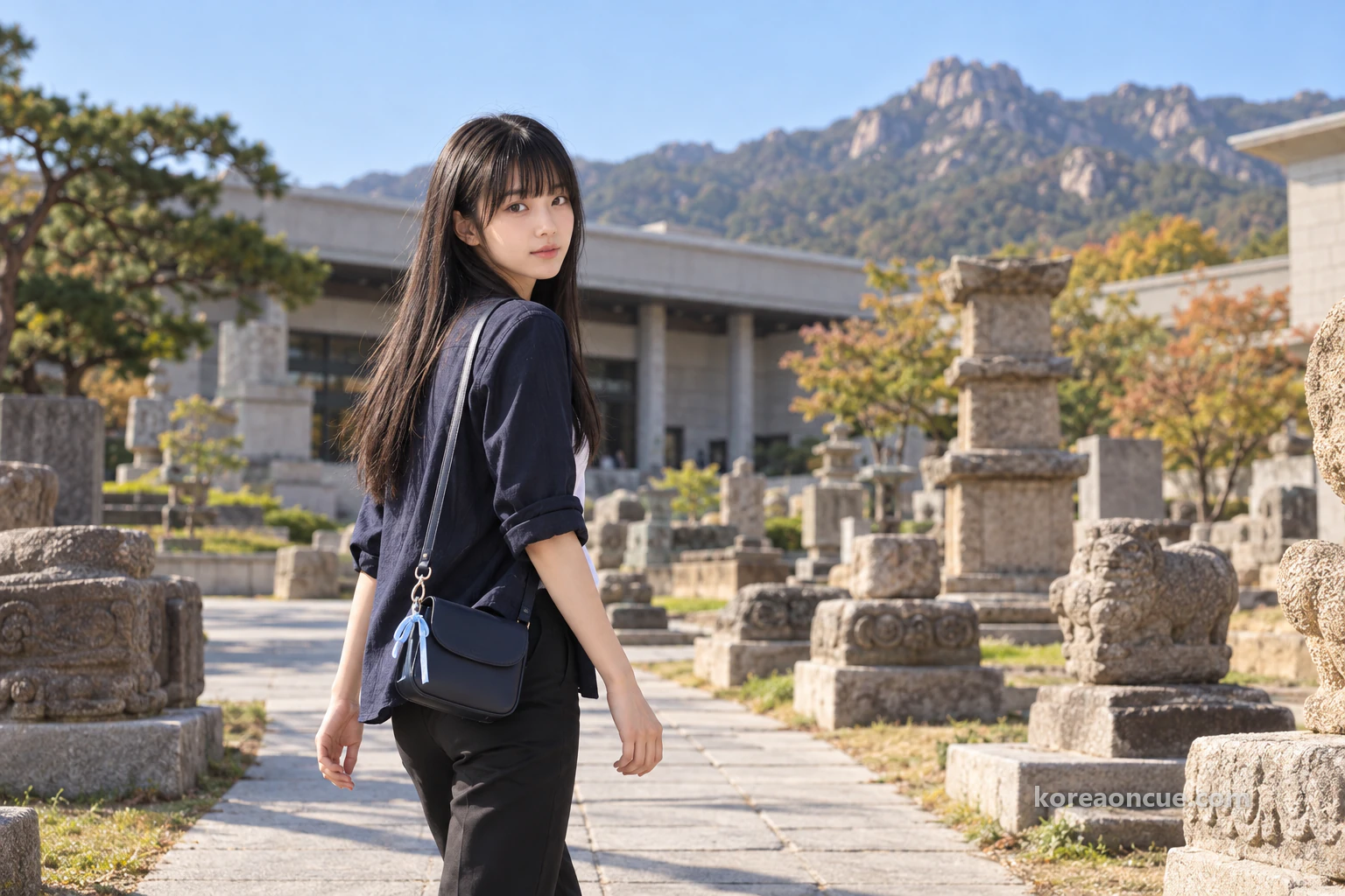 晴れた朝、小さな博物館の外にある低い古い石造物のあいだの小道を歩いて入っていくマヤの斜め後ろ姿。ぼんやりした建物と、その向こうの空に岩の稜線。編集イメージ。