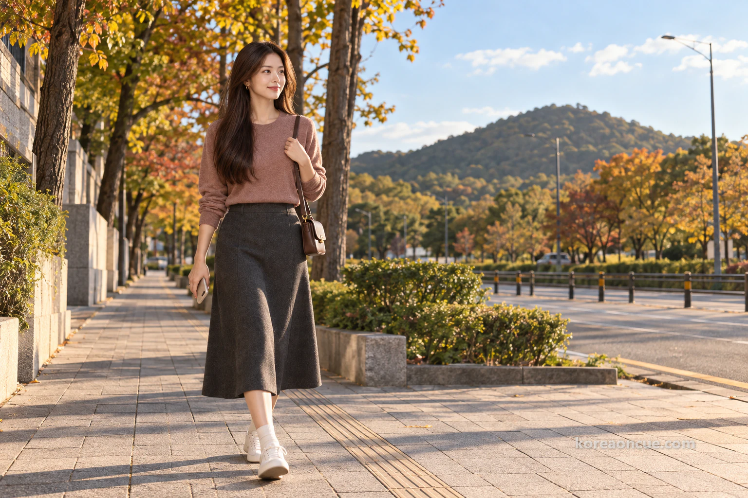 Mali small in the frame, seen obliquely from behind walking along a wide tree-lined pavement towards a park in slanting late-afternoon light, a low flat-topped green hill covered with trees in the distance under a wide sky. Editorial image.