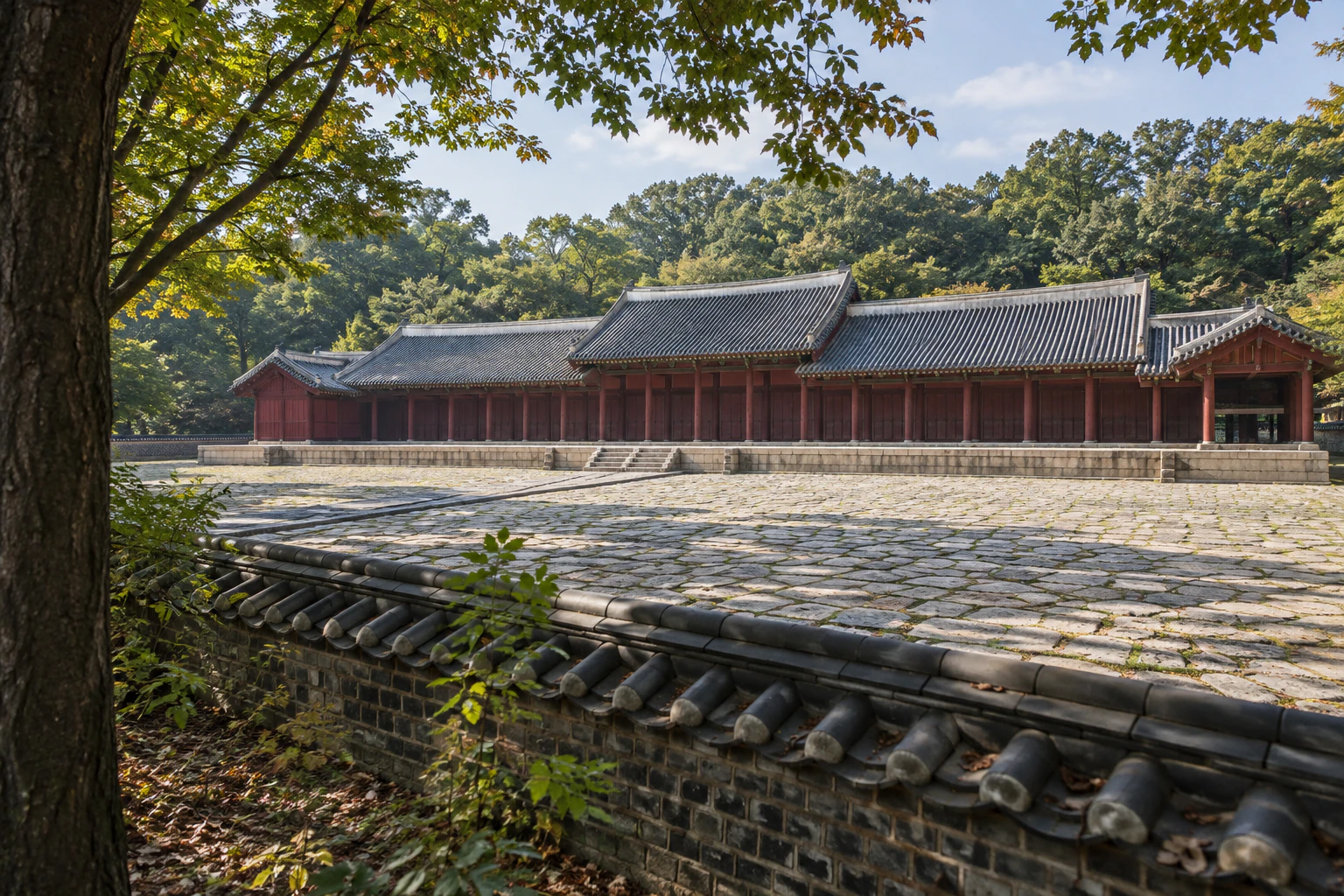 키 큰 나무들 사이로 기와를 얹은 낮은 벽돌담이 이어지고, 담 너머에 붉은 기둥의 긴 단층 건물 지붕이 보인다. 사람 없음. 문자는 넣지 않음. 편집 이미지.