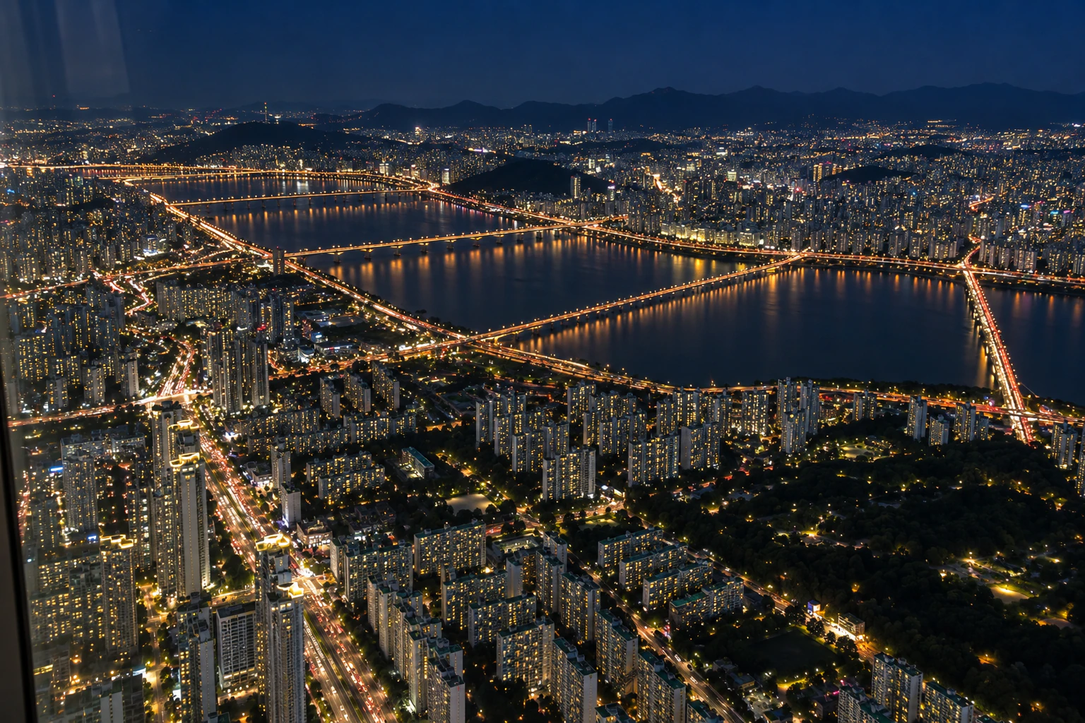 밤, 아주 높은 곳에서 본 넓은 강과 불이 켜진 여러 개의 다리, 강가의 불빛. 사람 없음. 문자는 넣지 않음. 편집 이미지.