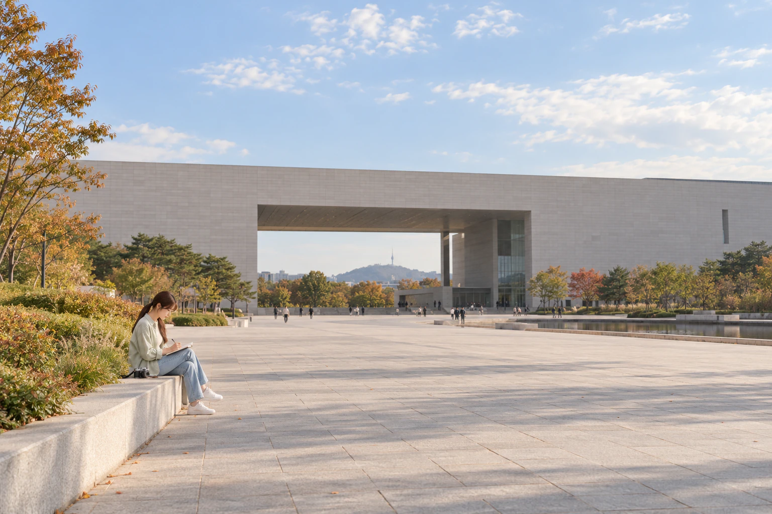 박물관 나들길이 바깥으로 열리는 자리에 작게 앉아 수첩에 쓰는 여성과, 멀리 보이는 길고 낮은 석조 건물. 편집 이미지.